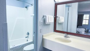 A bathroom with a bathtub, toilet, sink, and a mirror with a wooden frame. - Happy Extended stay (Madisonville)