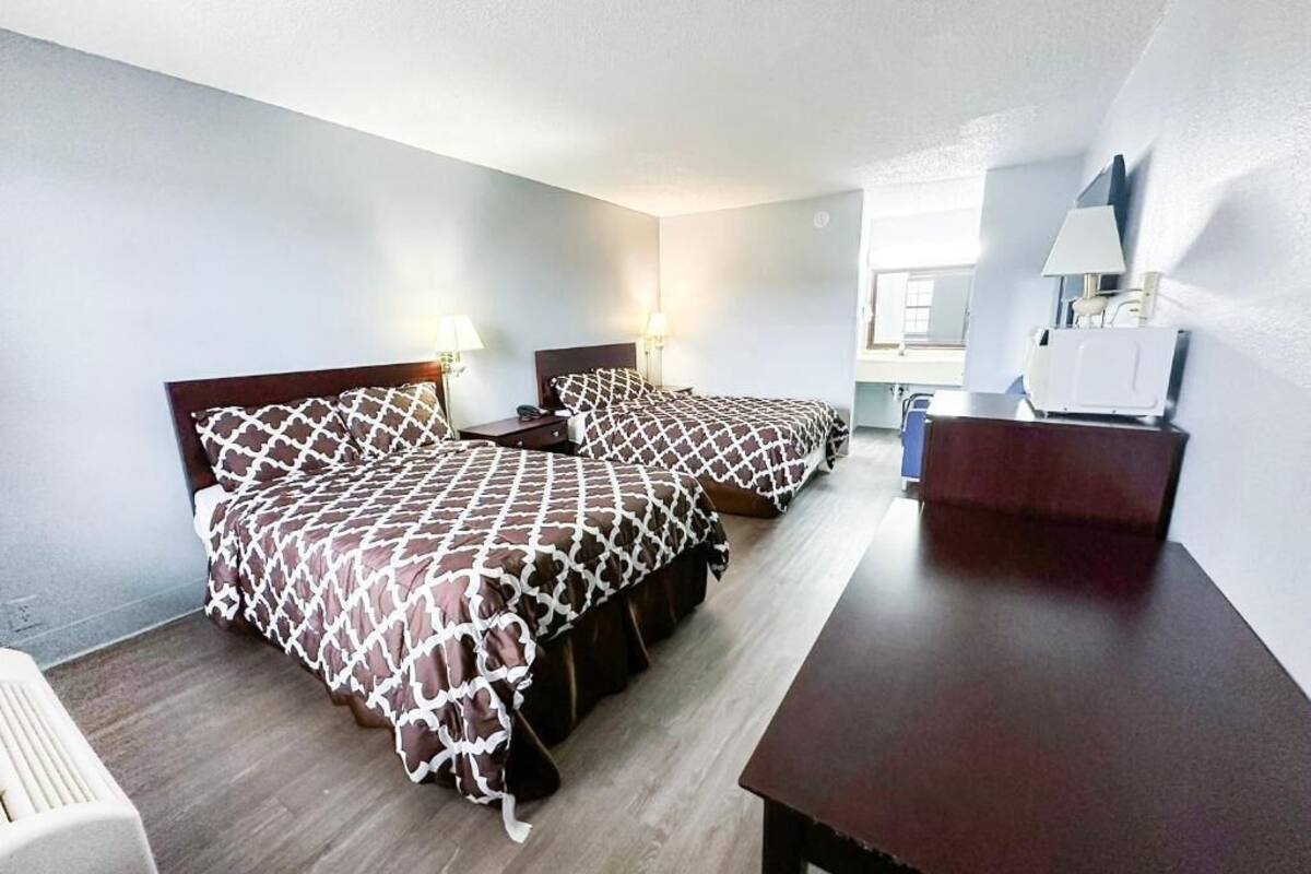 A hotel room with two beds, a desk, and a chair.