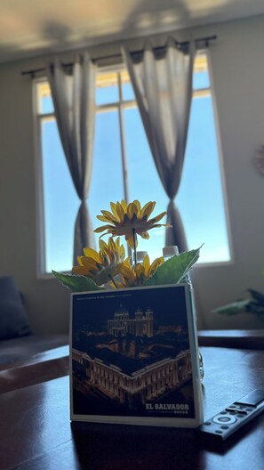 Een bloempot met gele bloemen op een tafel met een afstandsbediening.