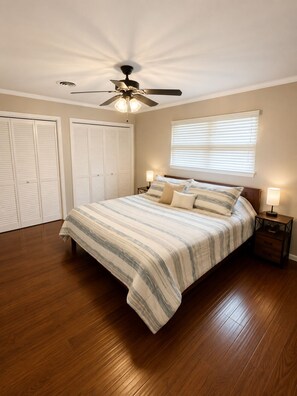 A bedroom with a bed, a ceiling fan, a window with blinds, and a wooden floor. - Spacious 3-bedroom house close to Texas Tech. Great neighborhood!! (Lubbock)
