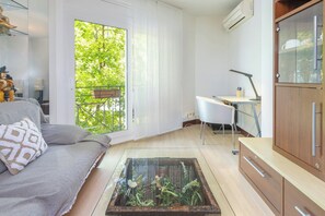 Ein modernes Wohnzimmer mit einer Couch, einem Glastisch mit Pflanzen, einem Schreibtisch und einem Schrank.