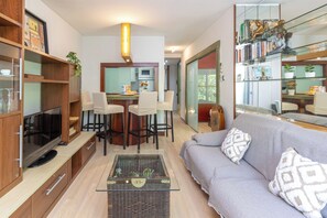 Ein modernes Wohnzimmer mit einer Couch, einem Couchtisch, einem Fernseher und einem Bücherregal.