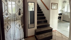 A staircase leading to an upper floor, a mirror on the wall, and a door with a decorative screen. - Cascina Moretta!!! It is a pleasure to have you here in the authentic heart of Monferrato. (Piemonte)