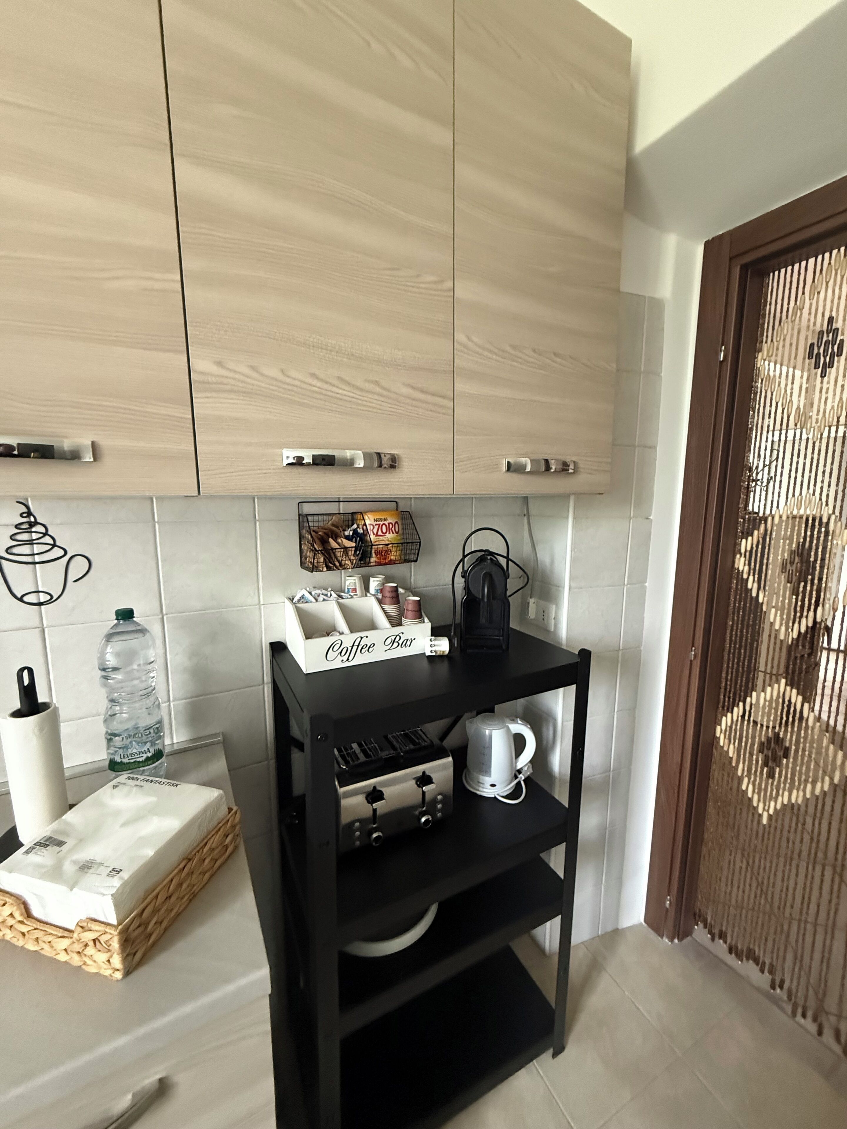 A kitchen with wooden cabinets, a coffee bar, a water dispenser, and a white coffee machine.