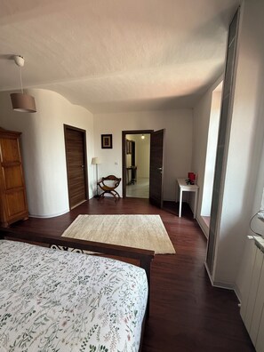 Une chambre Ă coucher avec un lit, une armoire en bois, un bureau et une chaise.