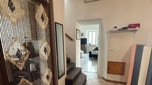 A hallway with a staircase leading to a living area, a radiator, and a welcome sign on the wall. - Cascina Moretta!!! It is a pleasure to have you here in the authentic heart of Monferrato. (Piemonte)
