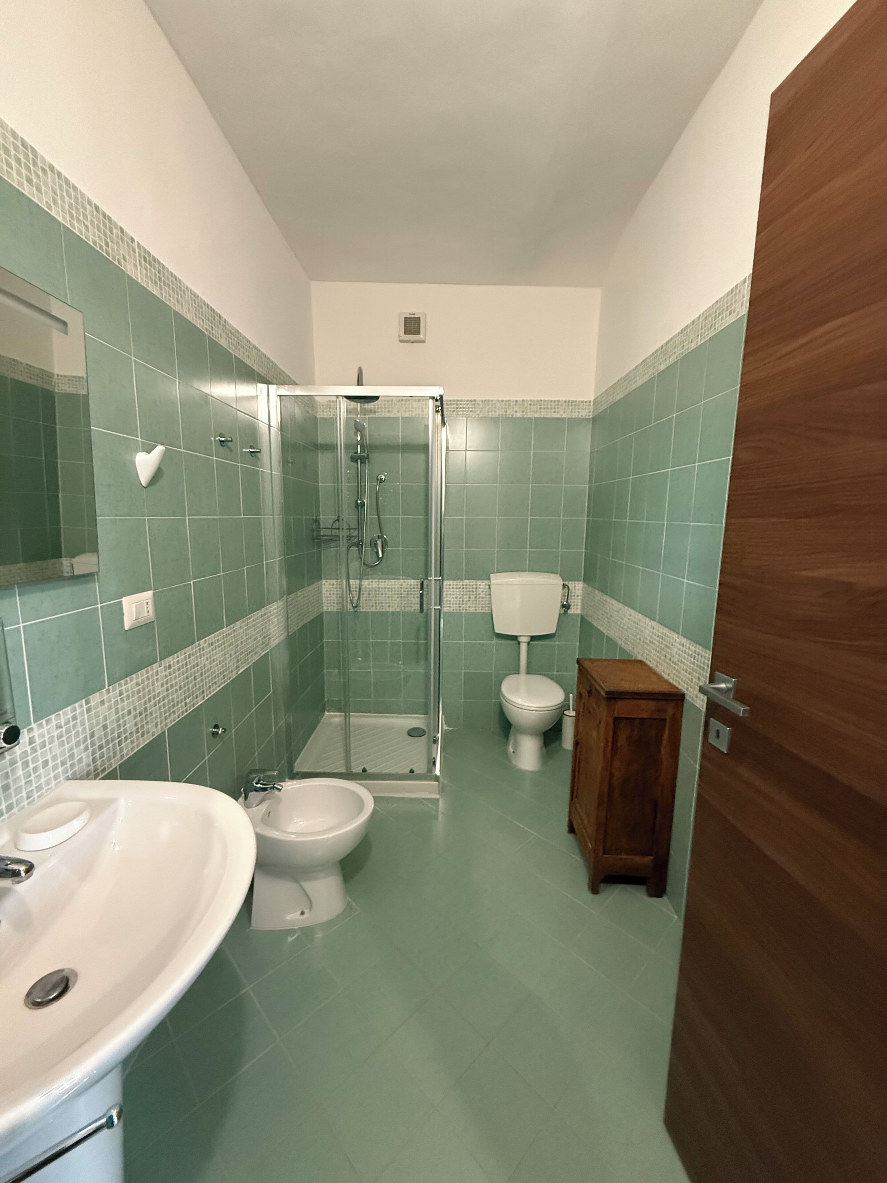Kylpyhuoneessa on suihku, kaksi wc:tä, pesuallas ja puinen kaappi.