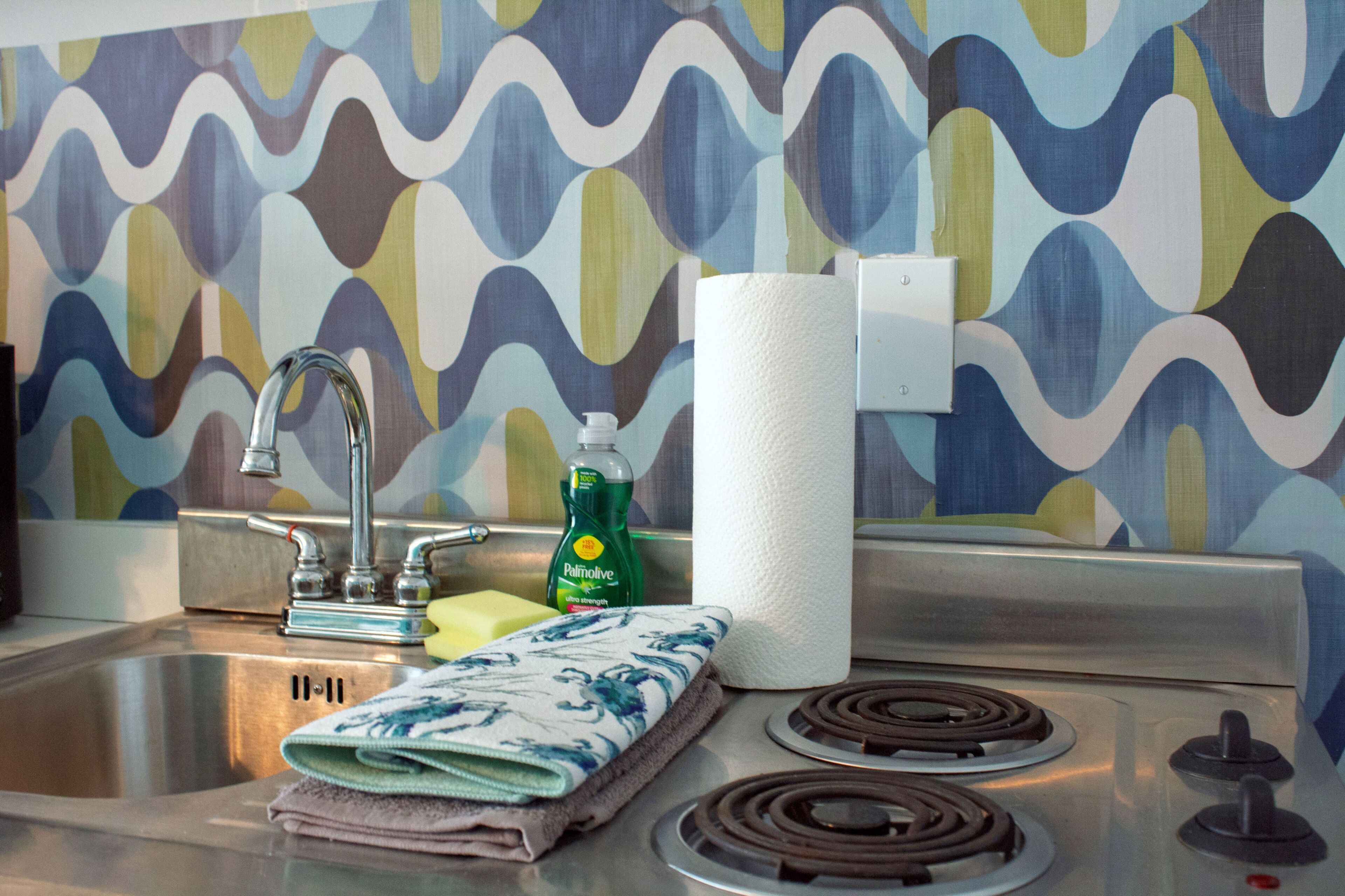 Kitchenette with an integrated stainless steel sink, cooktop, and patterned backsplash.