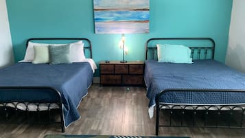 Ein Zimmer mit zwei Betten, einem Nachttisch, einer Lampe und einem Gemälde an der Wand.