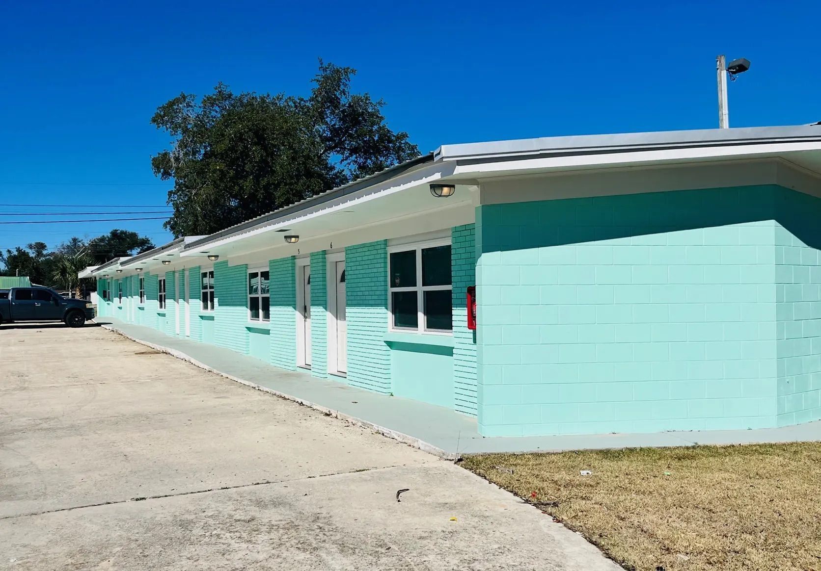 Exterior view of the single-story teal building along the concrete driveway.