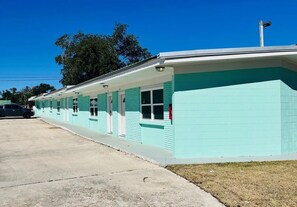 Exterior view of the single-story teal building along the concrete driveway.