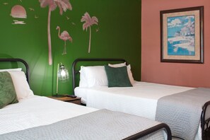 A bedroom features two beds positioned along a vibrant green accent wall.