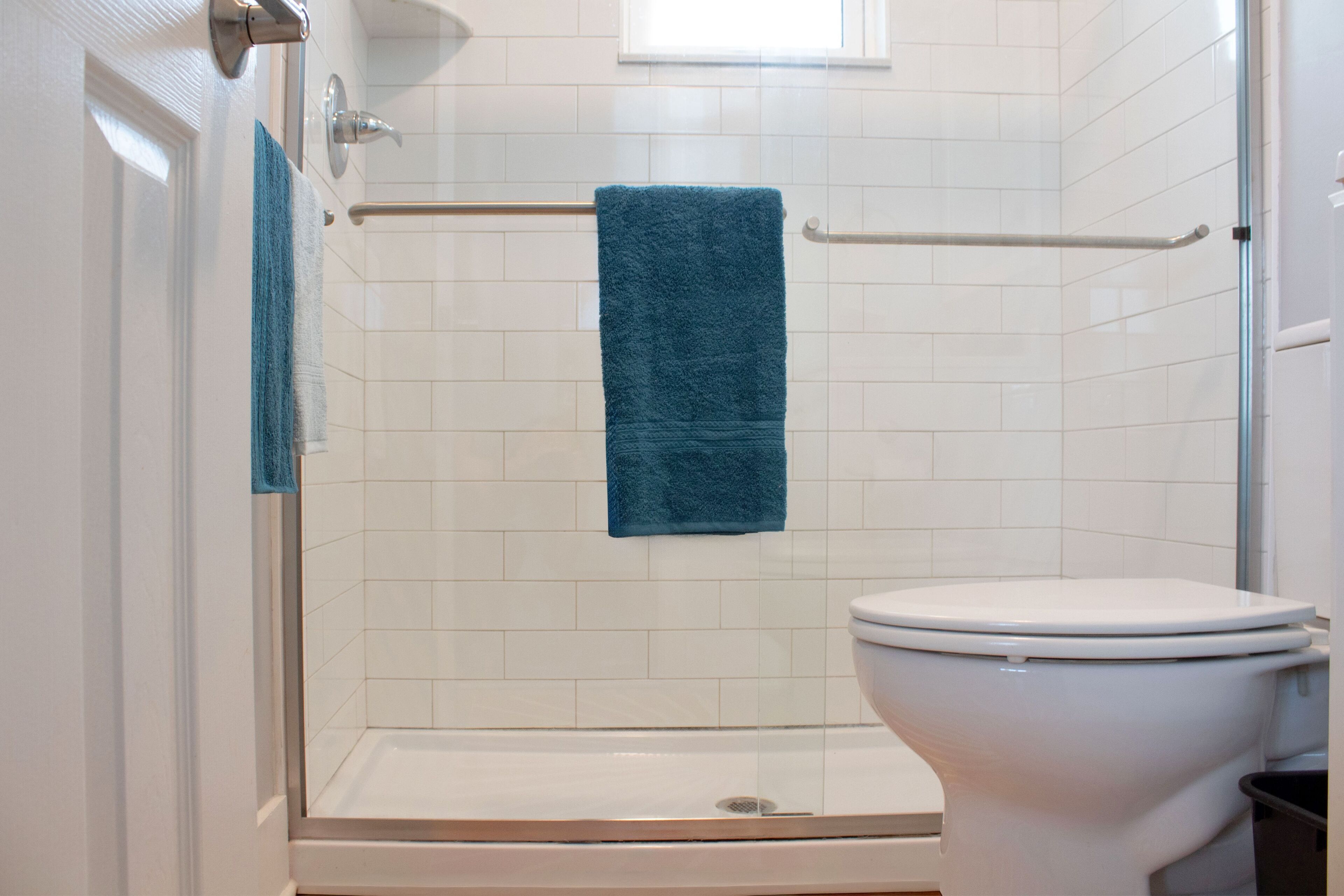 Bathroom featuring a glass walk-in shower with white subway tiles next to the toilet.