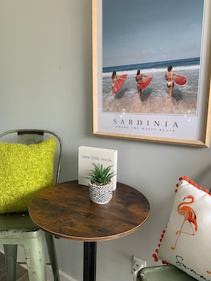 A small decorative seating vignette with a round accent table and framed wall art.