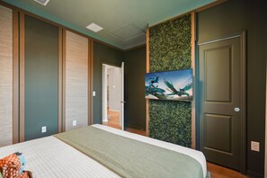 A bedroom with a bed, a door, and a wall with a green leafy design. - 8 BD / 6 BA / Windsor Cay 16095 CL (Clermont)