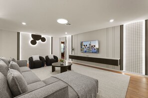 Ein modernes Wohnzimmer mit einem Ecksofa, zwei Sessel, einem Couchtisch und einem an der Wand befestigten Flachbildfernseher.