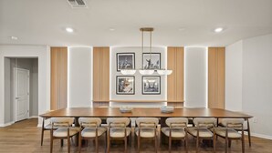 A dining room with a large wooden table, eight chairs, and a chandelier.