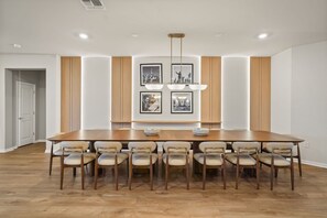 A dining room with a large wooden table, eight chairs, and a chandelier.