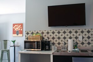 Kitchenette featuring a patterned tile backsplash, sink, microwave, and wall-mounted TV. - Florida Sunshine -Pet Friendly- Near Tyndall Base (Panama City)