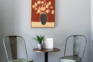 A small seating nook with two metal chairs, a round table, and wall art. - Florida Sunshine -Pet Friendly- Near Tyndall Base (Panama City)