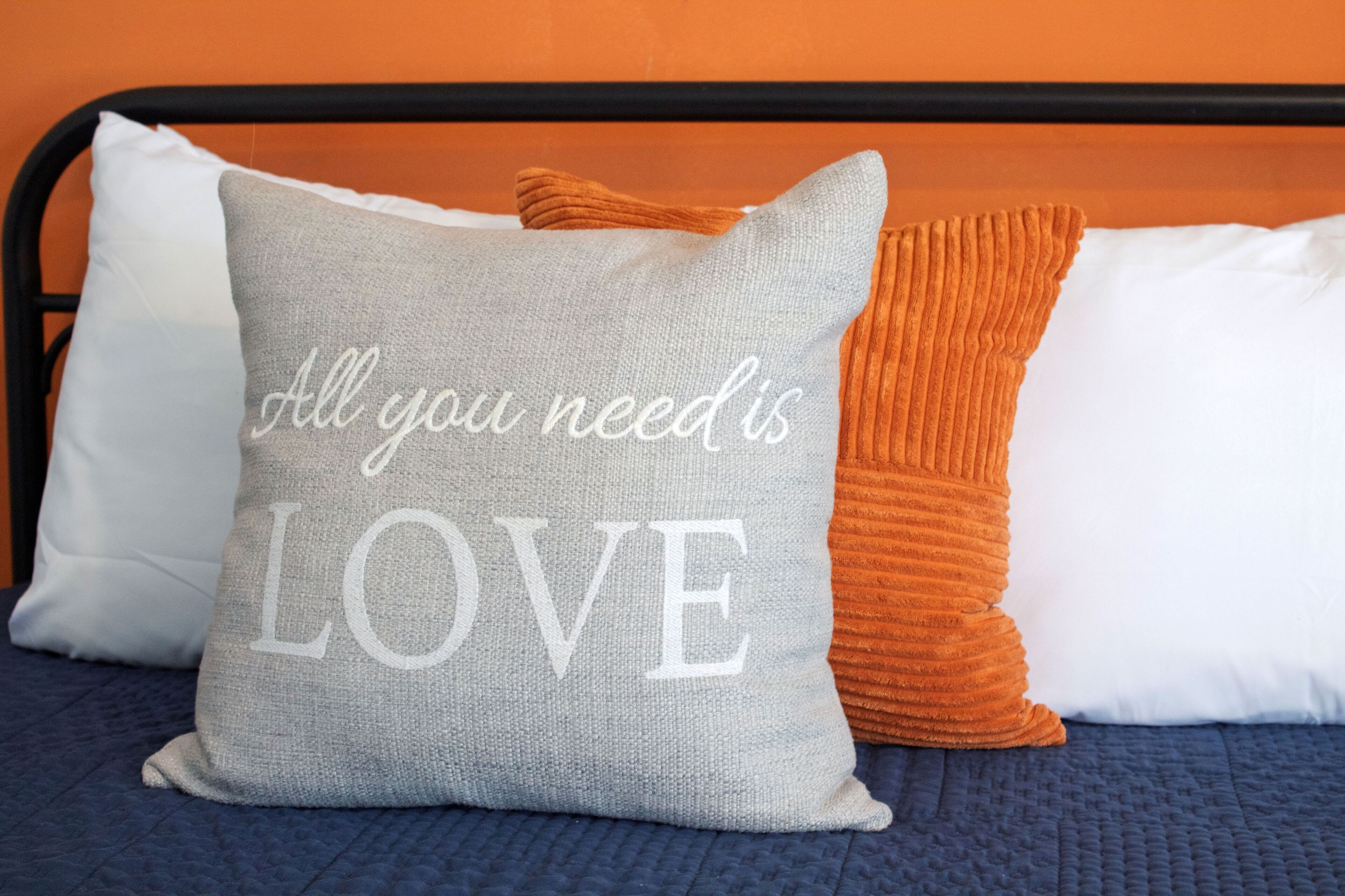 Decorative accent pillows rest against a black metal headboard.