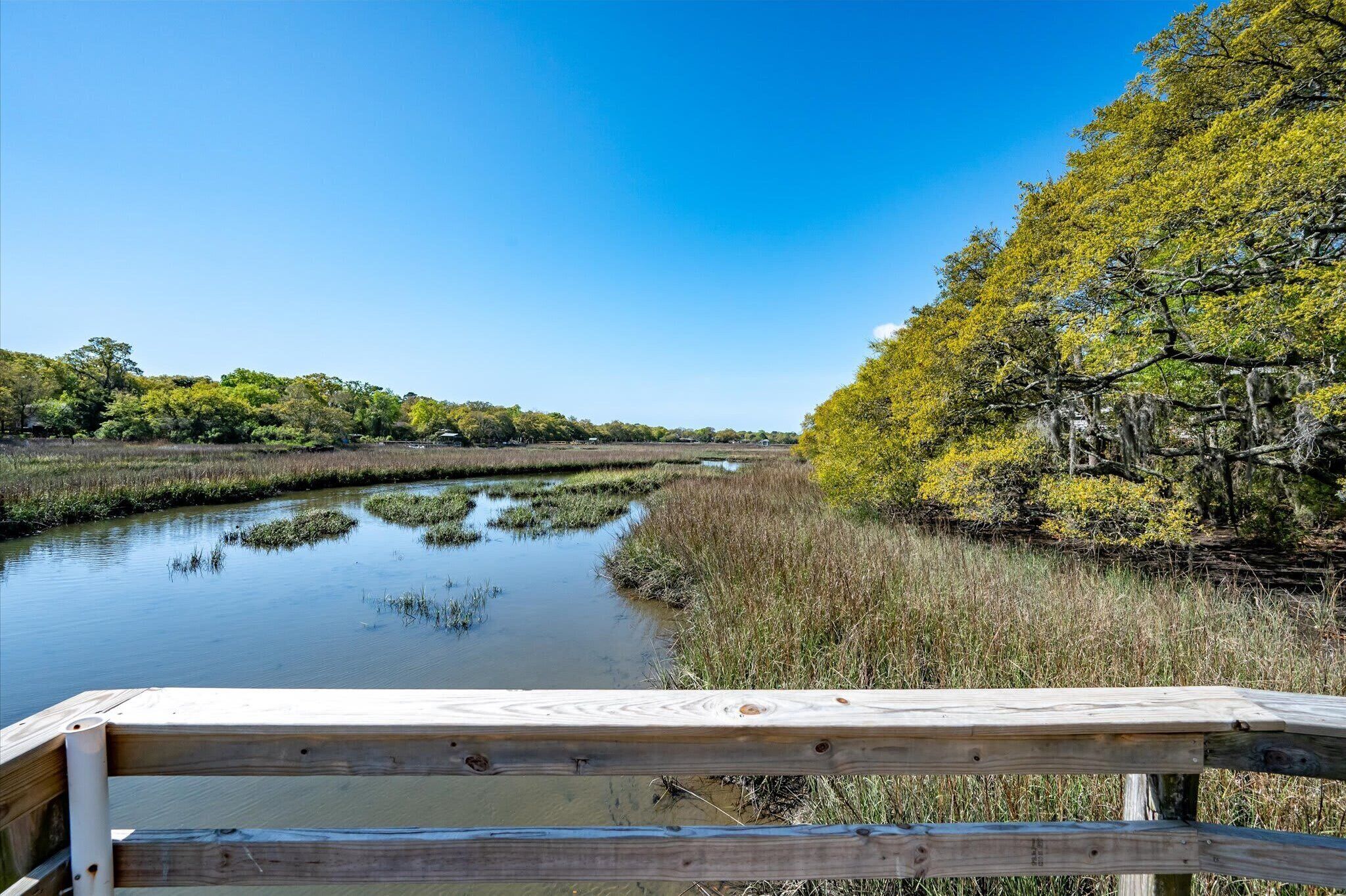 A wooden deck overlooking a calm water body with surrounding vegetation and trees.