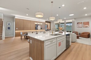 A modern kitchen with a central island, wooden cabinetry, and pendant lighting. - 10 BD/ 8 BA/ Windsor Cay (1003 CR) (Clermont)