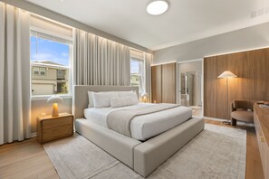 Un dormitorio moderno con una cama grande, mesitas de noche, un escritorio y zona de ducha.