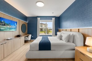 Una habitació d'hotel amb un llit, un escriptori, una televisió i una finestra amb vista a edificis.