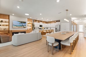 Una cocina moderna con armarios blancos, una mesa de comedor de madera y una isla grande.