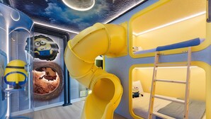Zona de juegos infantiles con tobogán, literas y decoración temática de Minions.