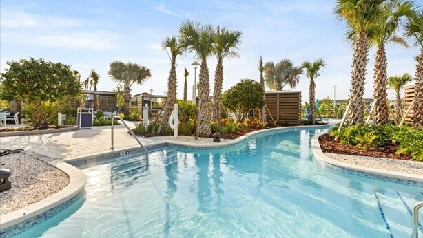Piscina con palmeras y una zona de estar techada.