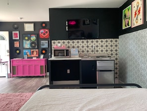 A compact kitchen with a microwave, refrigerator, and a small countertop. - Fall Weekend Getaways -Groovy Vinyl -East Bay Inn (Panama City)