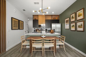 A modern kitchen with a central island, wooden chairs, and a dining table. - 3 BD/ 3 BA/ The Hub At Westside (3349 TT) (Kissimmee)