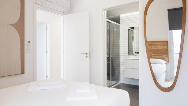 Ett modernt hotellrum med en säng, ett badrum med en glasdörr och en stor spegel.