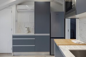 A modern kitchen with built-in appliances, a marble countertop, and a wooden table. - Romantic Gem Avenidas Novas – GEM Residence (Lisbon)