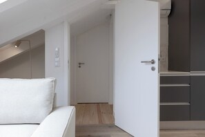 A modern room with a bed, a door leading to a kitchen, and a staircase. - Romantic Gem Avenidas Novas – GEM Residence (Lisbon)