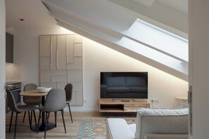 A modern living space with a dining area, a flat-screen TV, and a skylight. - Romantic Gem Avenidas Novas – GEM Residence (Lisbon)