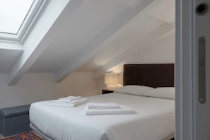 A modern hotel room with a skylight, a neatly made bed, a bedside lamp, and a headboard. - Romantic Gem Avenidas Novas – GEM Residence (Lisbon)