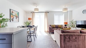 A modern living room with a sofa, dining area, and kitchen.