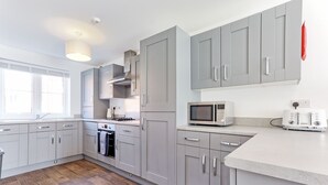 A modern kitchen with grey cabinets, a microwave, a toaster, and a stove.