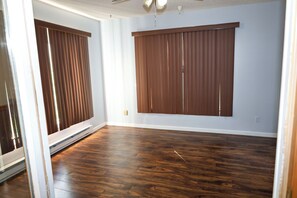 A room with wooden flooring, a large window with blinds, and a ceiling fan. - Timeless in Tennessee (Jonesborough)