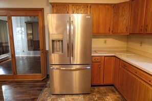 A stainless steel refrigerator with a water dispenser, wooden cabinets, and a kitchen counter. - Timeless in Tennessee (Jonesborough)