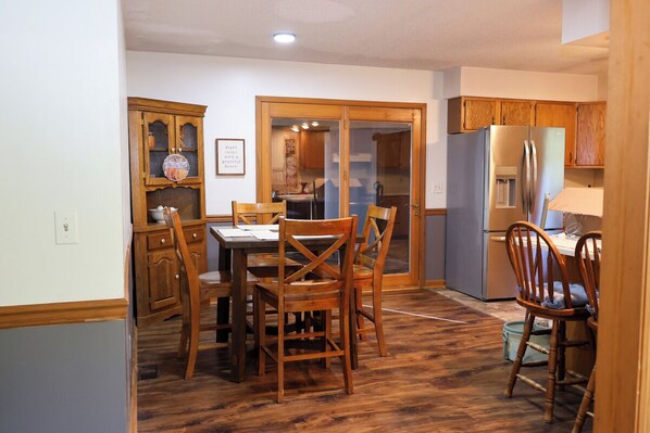 A kitchen with wooden cabinets, a dining table with chairs, and a refrigerator. - Timeless in Tennessee (Jonesborough)