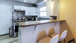 A kitchen with white cabinets, a granite countertop, stainless steel appliances, and pendant lighting. - 3BR Near Takoma Metro & DC Hospitals (Washington)