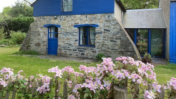 Una casa in pietra con facciata blu e due finestre con persiane blu.