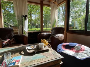 Una habitación con un ventanal grande, una mesa con una bandeja de comida, una silla y un libro.