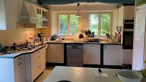 Una cucina dotata di lavastoviglie, piano cottura e diversi elettrodomestici. Si apre una finestra con vista su del verde.
