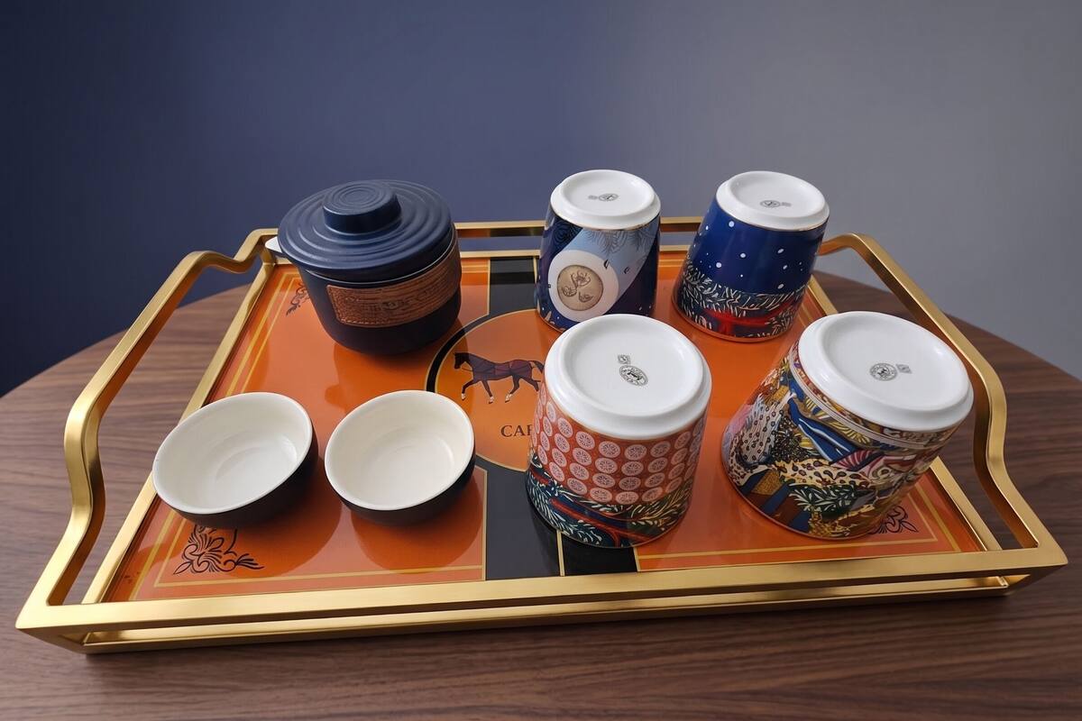 A tray with various ceramic items including cups and a bowl, arranged on a table.