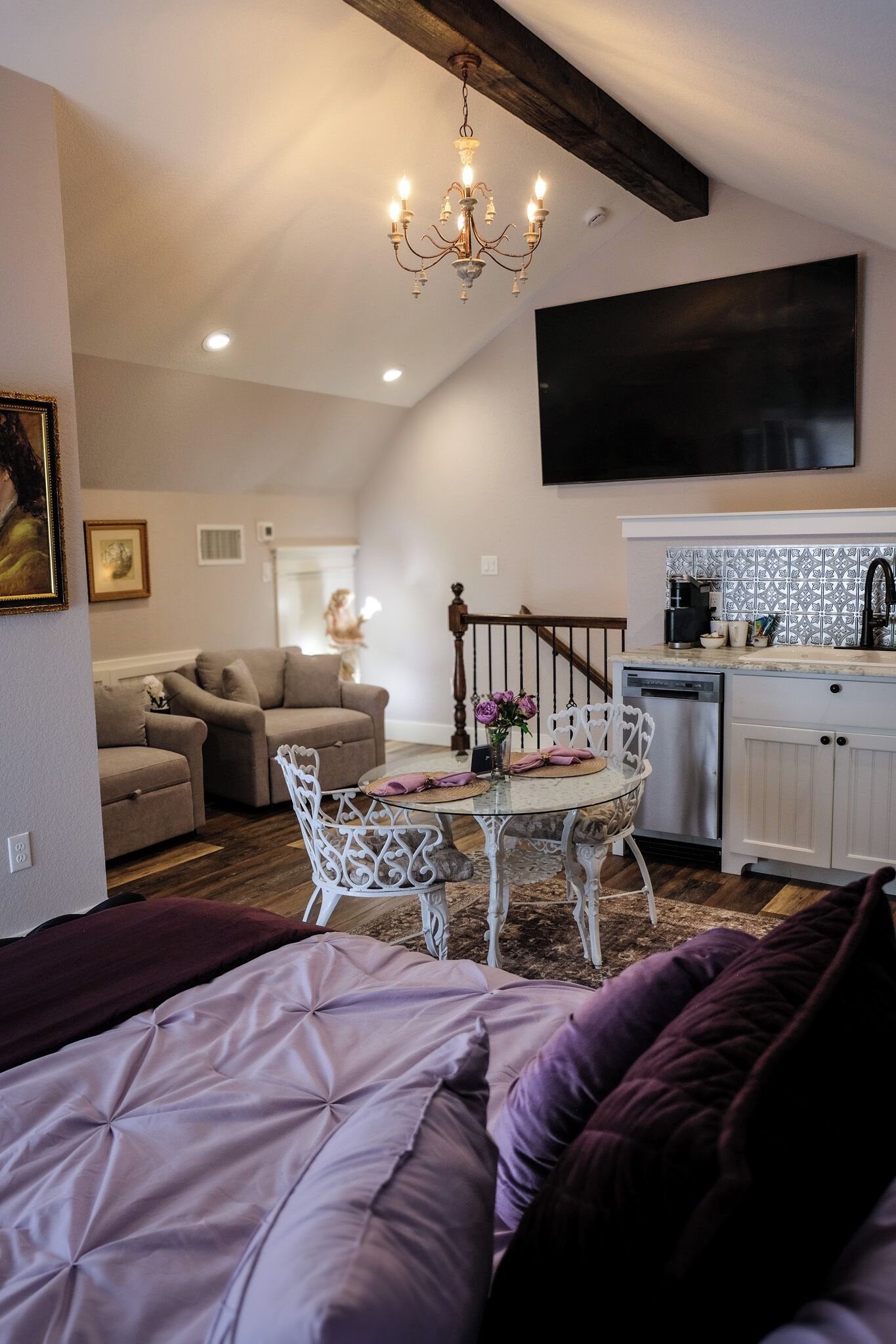 Una sala acogedora con una cama, una mesa de comedor con sillas, una zona de cocina y una escalera.